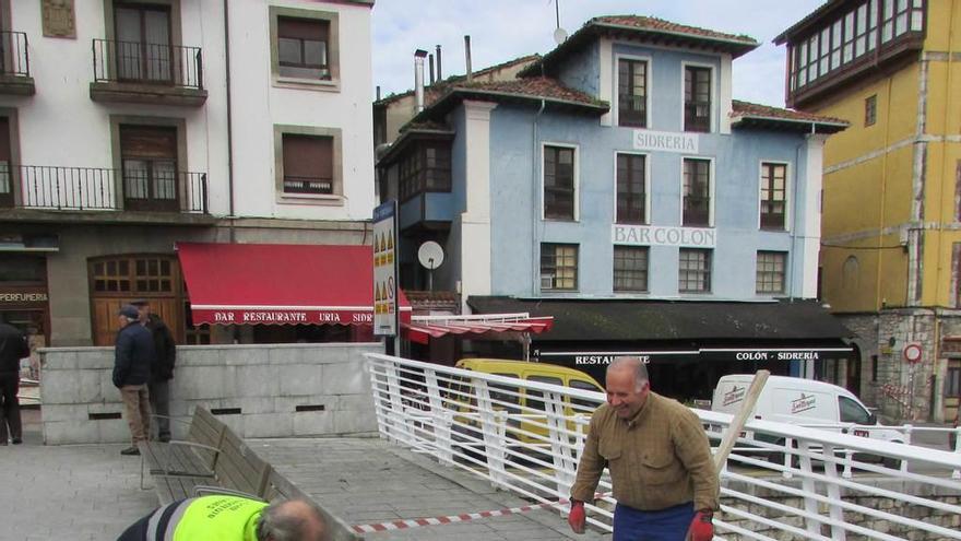 Dos operarios reparando las baldosas dañadas en el puente llanisco, ayer.