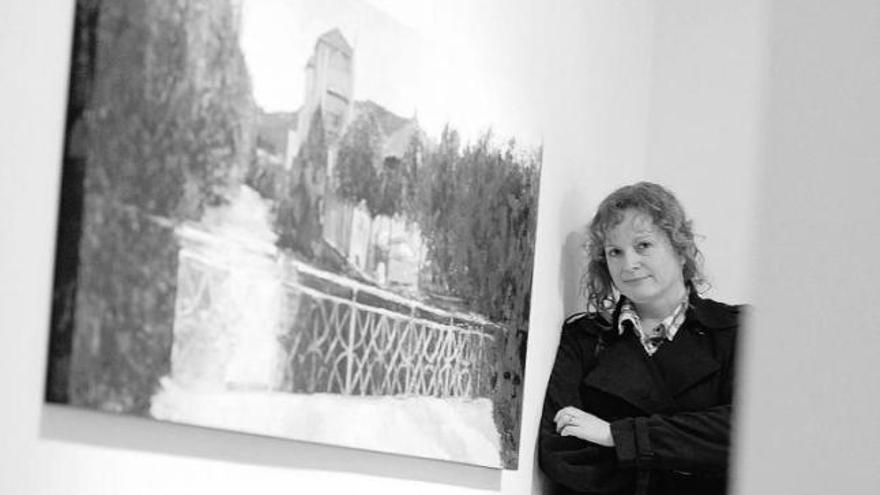 María Jesús Rivero, junto a uno de sus cuadros sobre Trubia colgados en la sala de exposiciones de Cajastur en Mieres.
