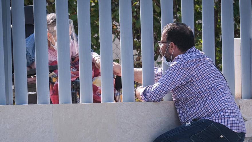 Un hombre conversa con un familiar desde el exterior de una residencia