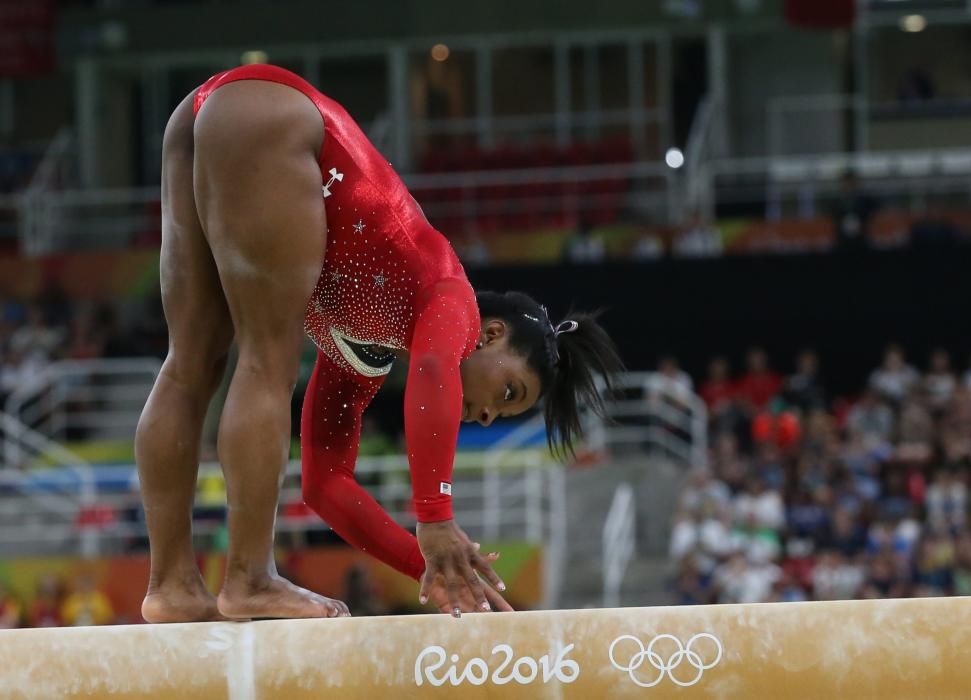 Simone Biles se vale de sus manos para no caer de la barra.