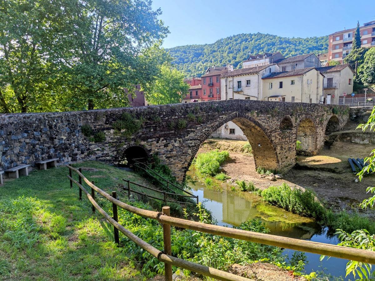 Puente medieval de piedra que cruza un tranquilo arroyo en Ripoll, Cataluña