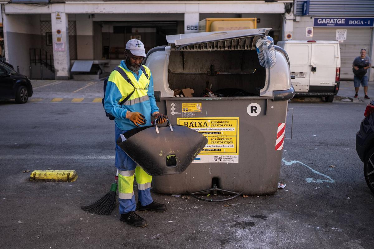 Un contenidor d'escombraries i un treballador municipal del servei en el barri de Sant Roc de Badalona.