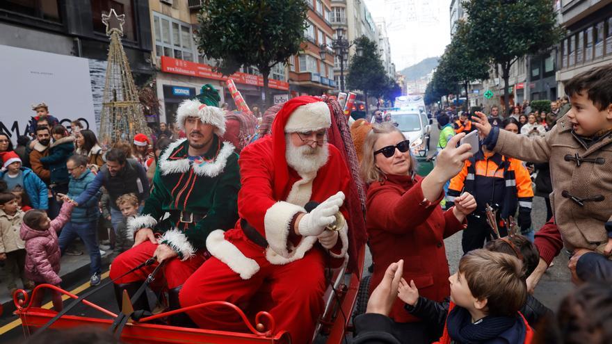 Papá Noel posando para fotos y saludando a los niños a su paso por la calle Uría.