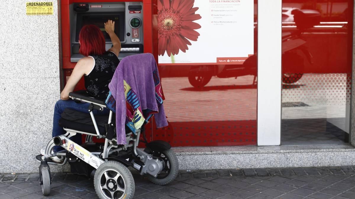 Una mujer con discapacidad saca dinero en un cajero.
