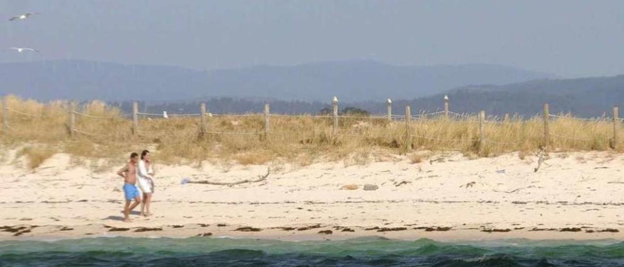 Dos visitantes pasean por una de las idílicas playas de Areoso, en A Illa de Arousa. // Noé Parga