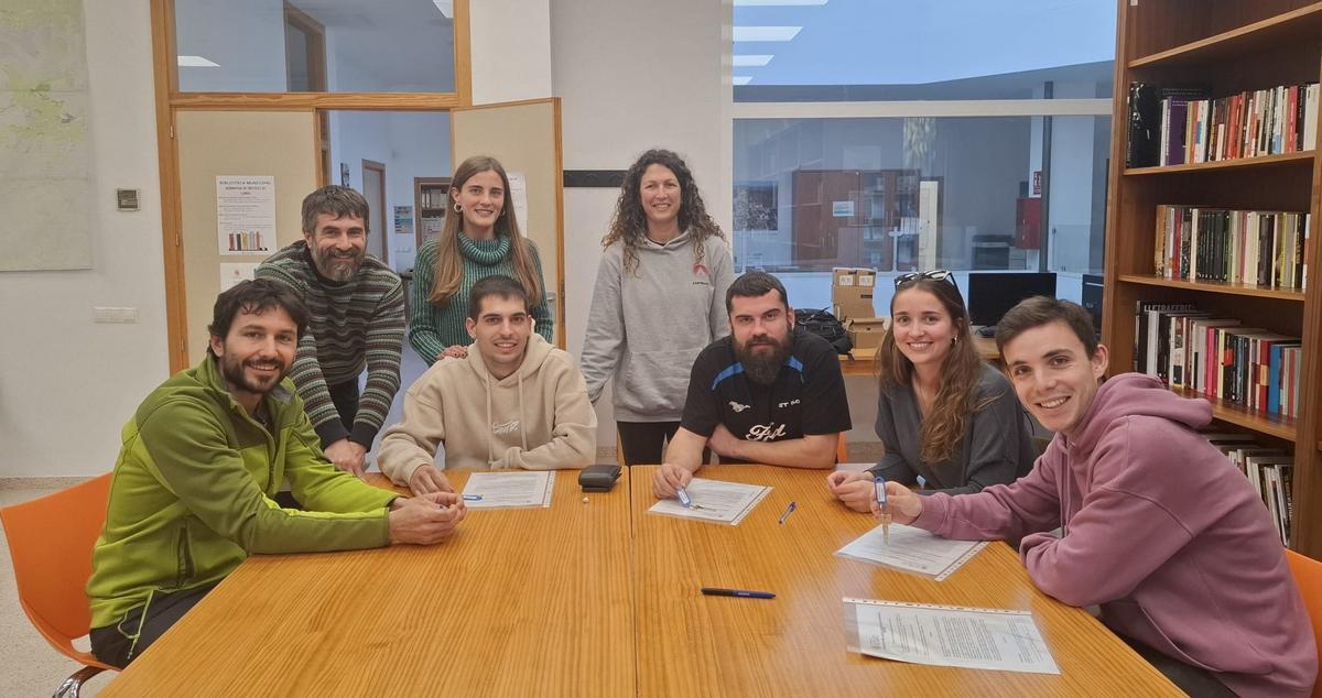 Los cuatro jóvenes, sentados junto al alcalde, en el momento de firmar el contrato de las habitaciones
