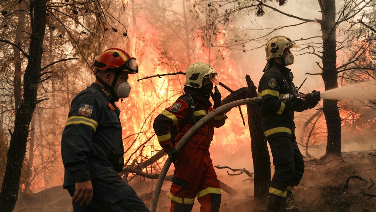 Tres bomberos trabajan para sofocar un fuego en la isla de Evia.