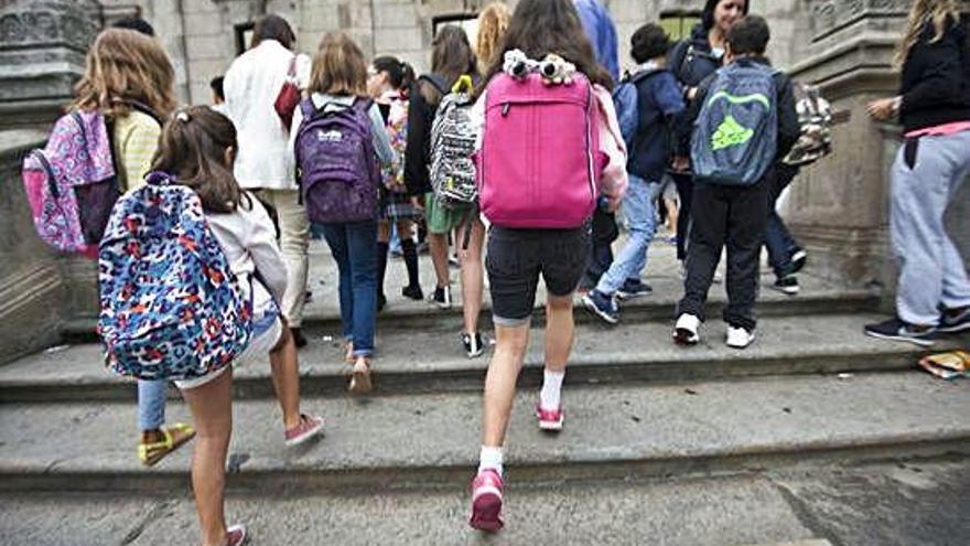 Alumnos con mochilas en la entrada de un centro de enseñanza.