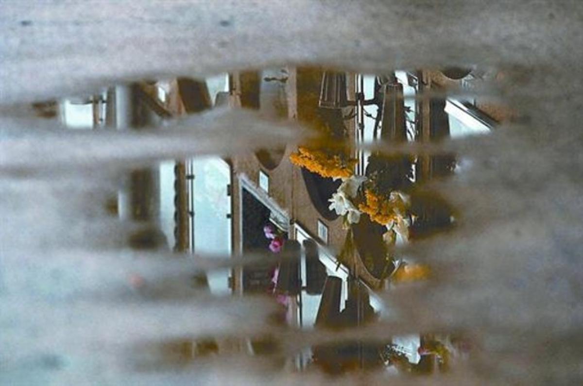 Flors i nínxols del cementiri del Poblenou de Barcelona reflectits en un bassal un dia de Tots Sants.