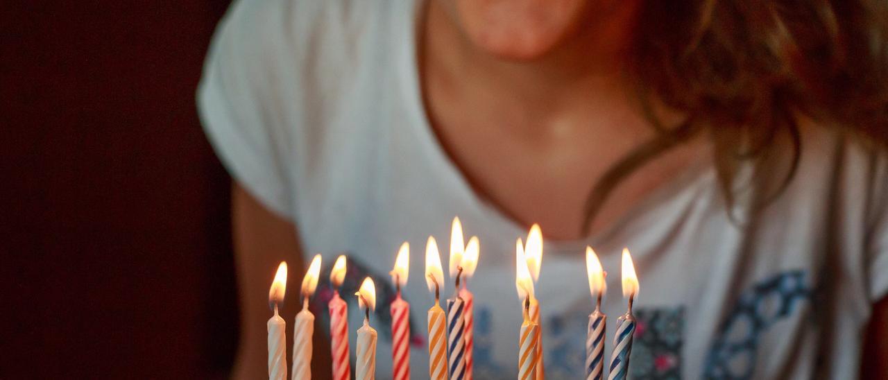 Una mujer sopla velas en un pastel de cumpleaños