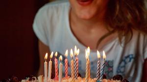 Una mujer sopla velas en un pastel de cumpleaños