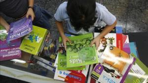 Dos niñas revisan unos libros de texto depositados sobre una mesa.