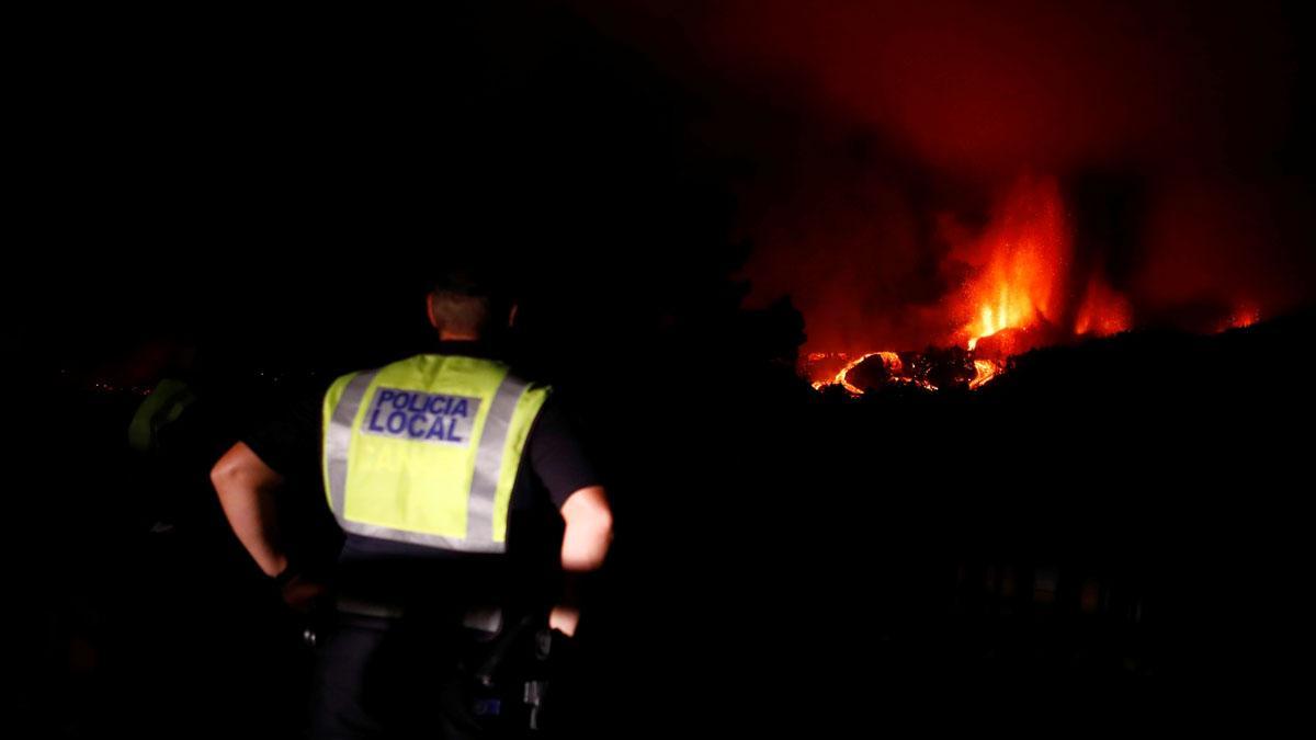 Un agente de la policía local sigue la erupción del volcán de La Palma en la distancia