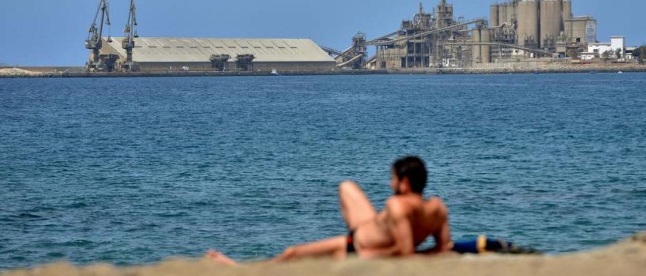 Un bañista  en la playa de Santa Águeda con la cementera al fondo.