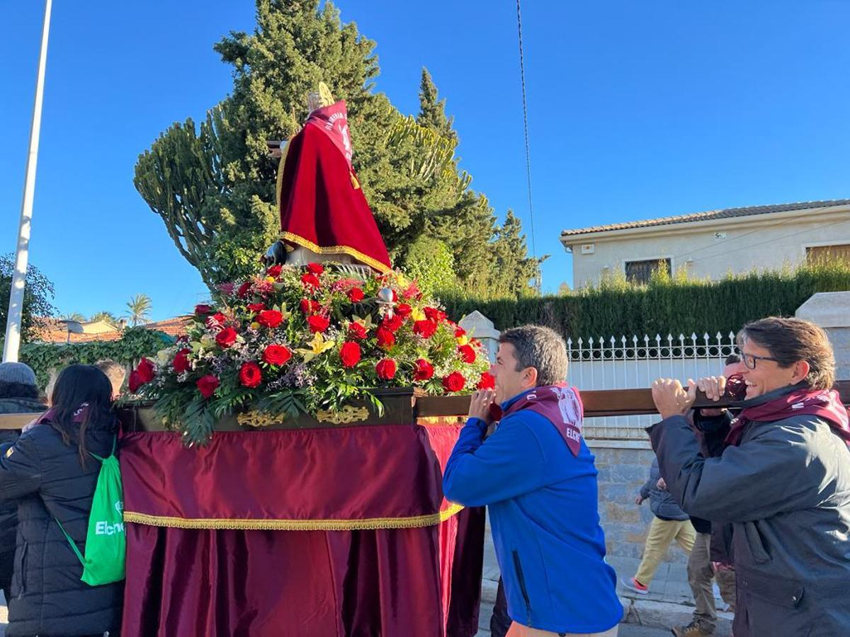 El presidente del PP, Carlos Mazón, llevando junto a Juande Navarro el trono de San Antón, en Elche