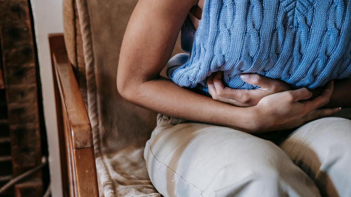 Una mujer cogiéndose la barriga por dolor.