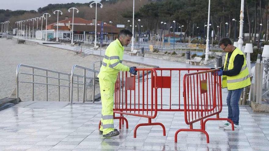 Operarioros municipales, ayer, colocando las vallas para clausurar el paseo y la playa de Samil por orden del gobierno local. // José Lores