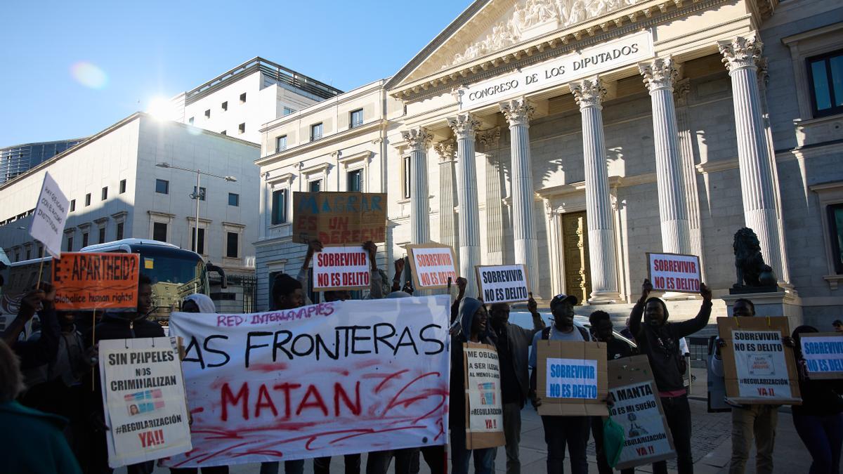 Varias personas se concentran frente al Congreso de los Diputados en Madrid, en defensa de la ILP Regularización Ya mientras se debate la iniciativa.