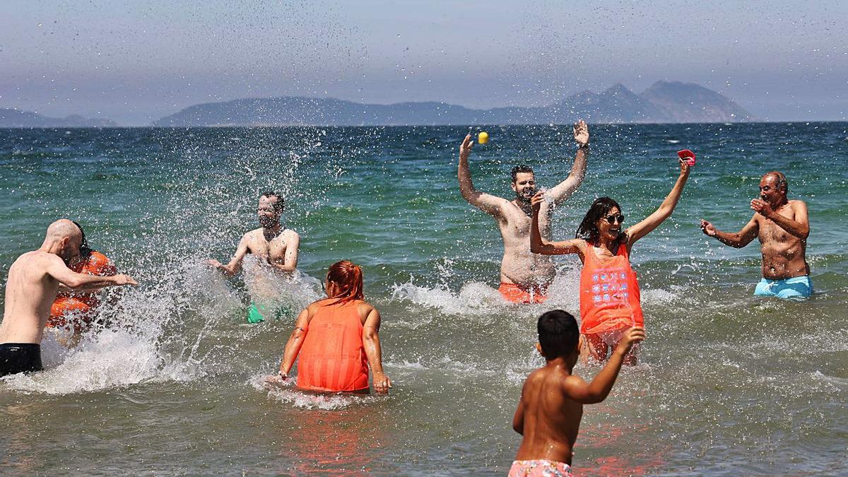 Bañistas que participaron en el chapuzón solidario, esta mañana en Samil.