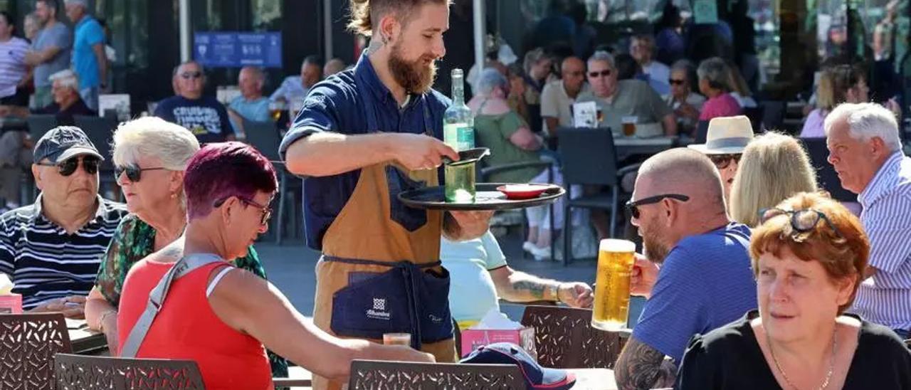 Un camarero atiende a un grupo de clientes en una terraza.