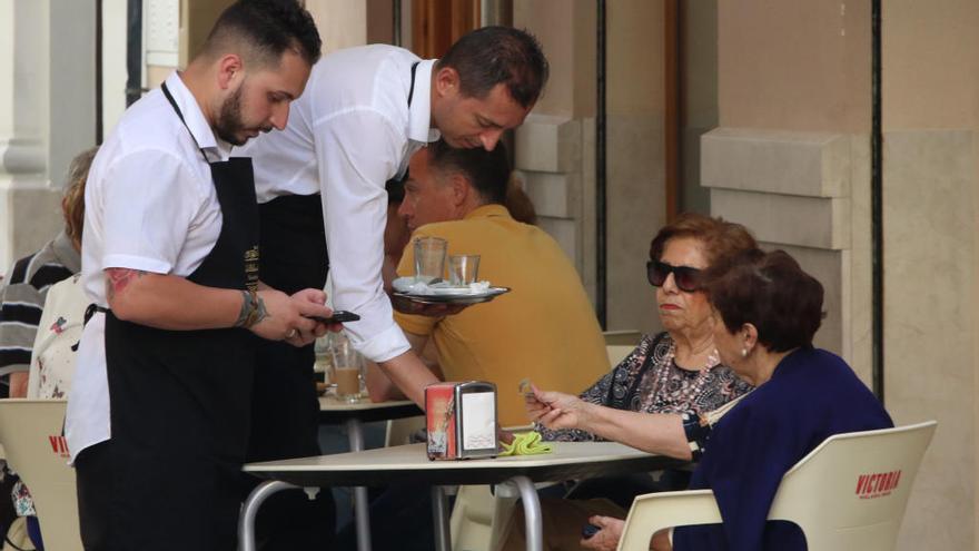 Camareros sirven a unas clientas en Málaga.