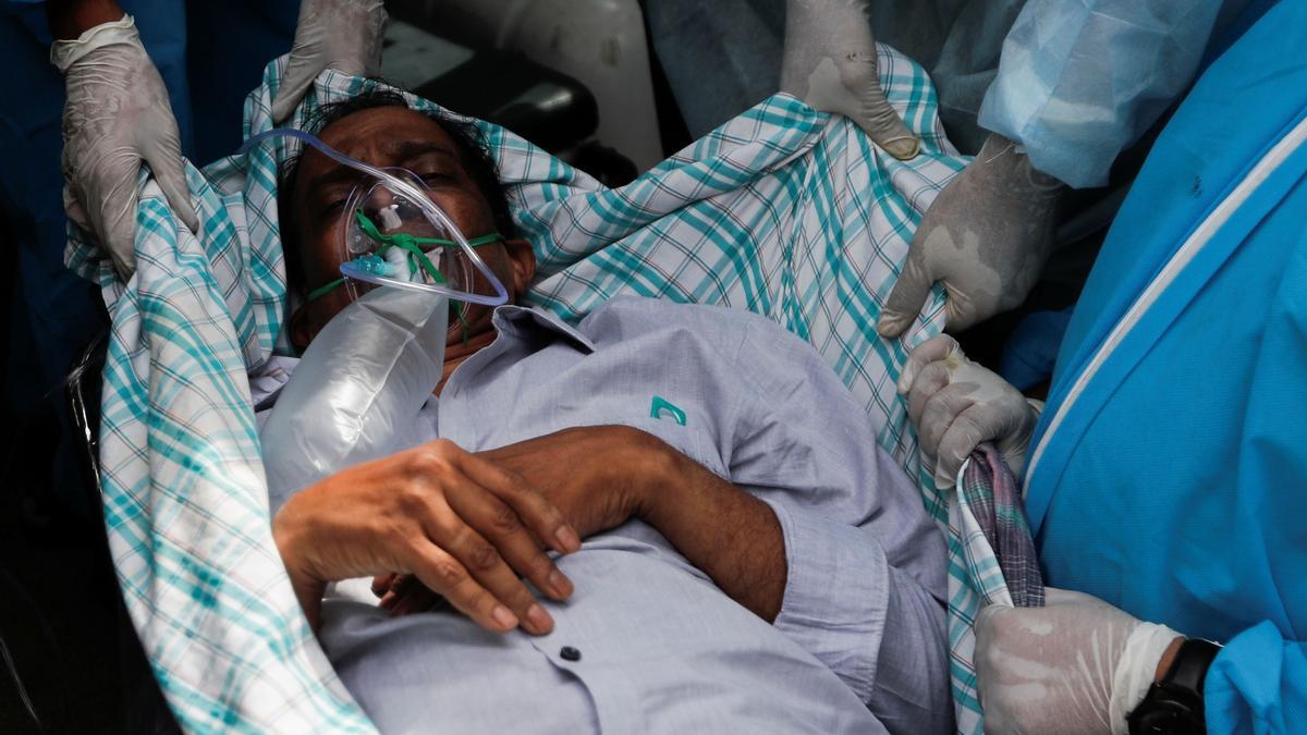 Un enfermo de covid es evacuado del hospital indio incendiado este viernes.