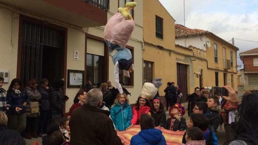 Niños y vecinos de Fuentes de Ropel manteando un pelele en una calle de la localidad.