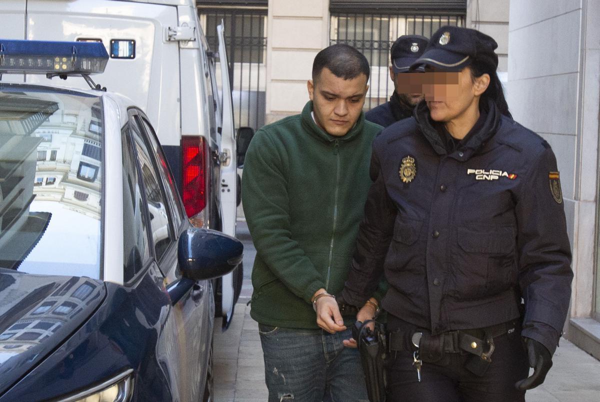 El acusado declarado culpable es trasladado por la Policía al juicio.