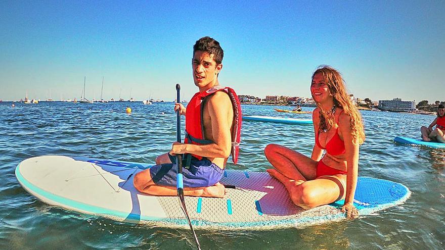 Adrián Salazar rema de genolls sobre una taula de paddle surf a la badia de Talamanca.a. | SUP IBIZA