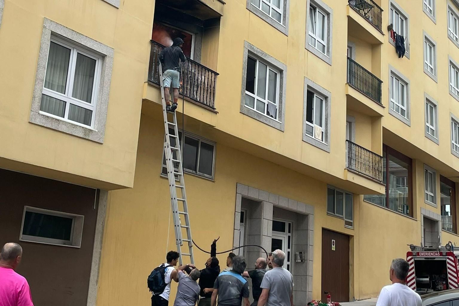 Vecinos intentando sofocar las llamas en el piso donde se originó el incendio en Laxe
