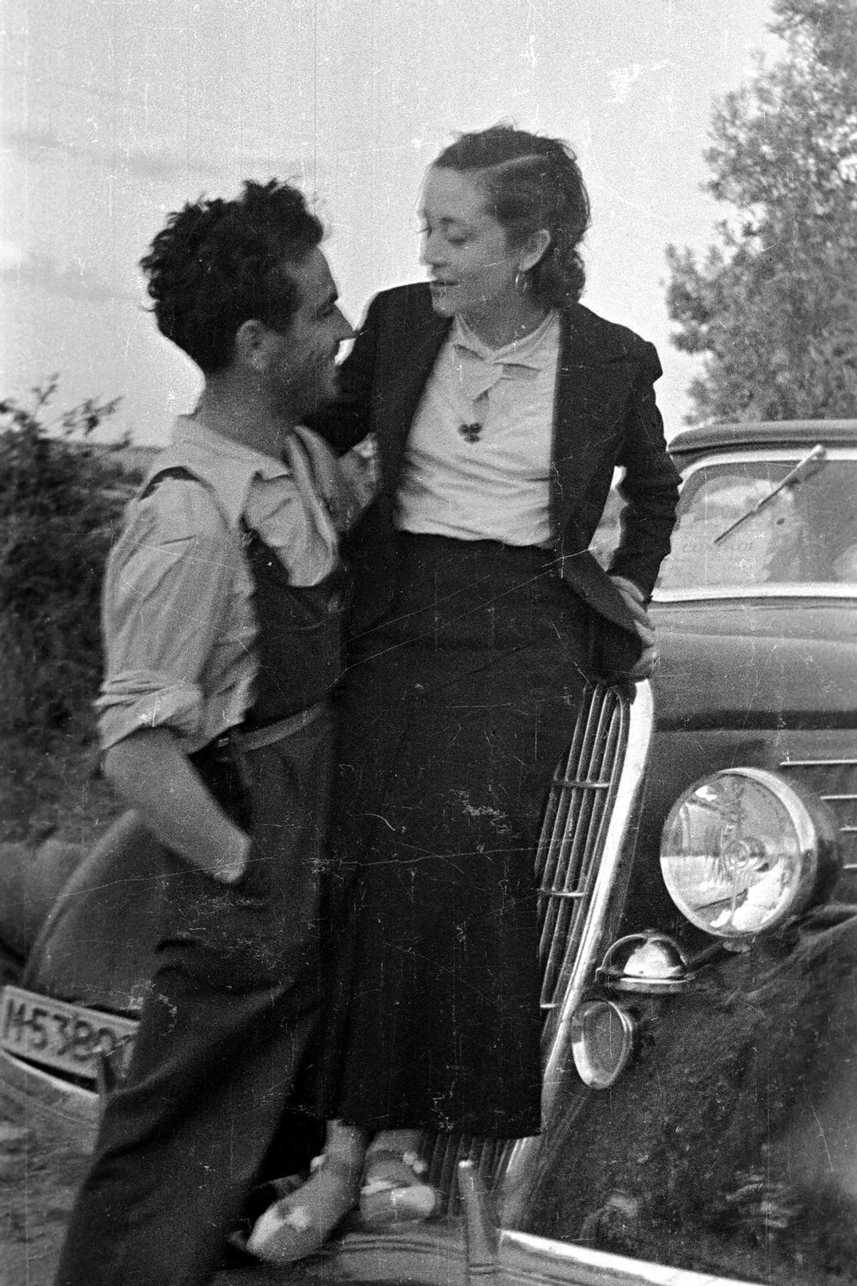 Arturo y Julia se abrazan ante un coche con las lunas delanteras tiroteadas.