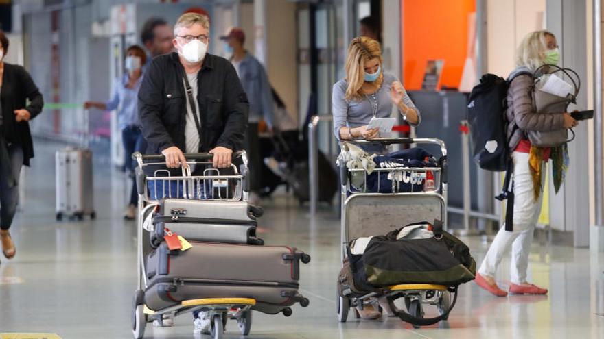 Un grupo de pasajeros en el aeropuerto de Ibiza con la mascarilla puesta.