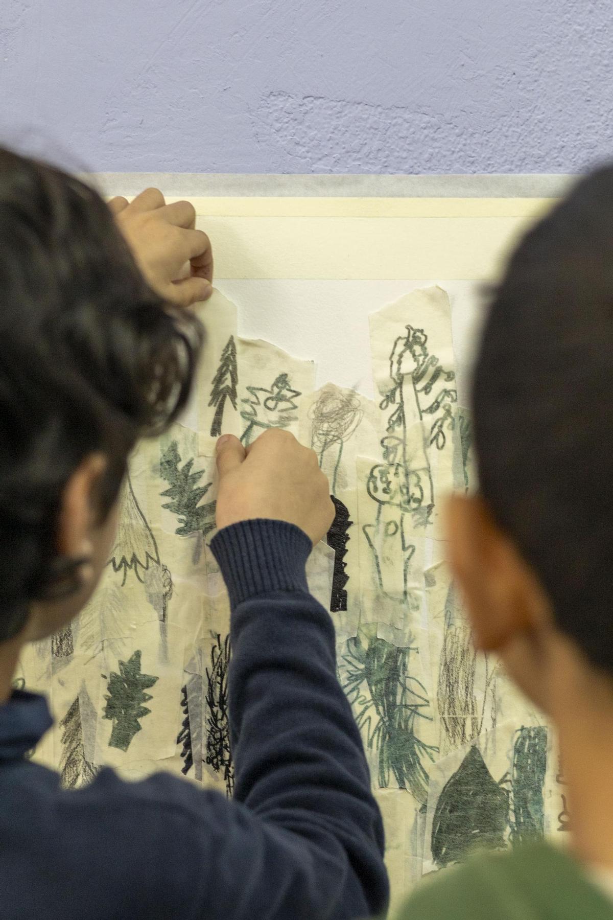 Dos escolares añadiendo sus árboles a la obra colectiva.