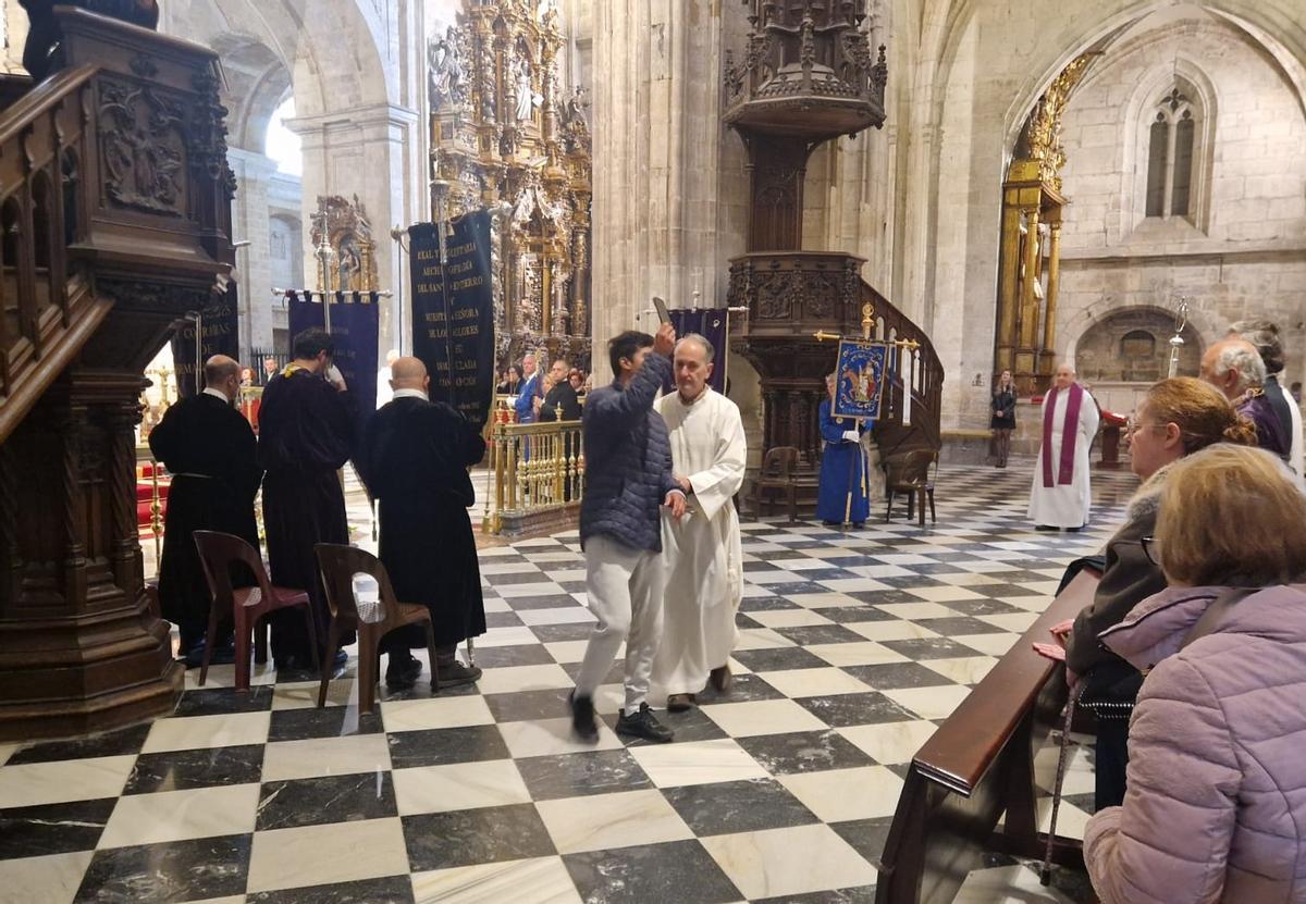El momento del desalojo mientras muestra el móvil a los asistentes a la misa.