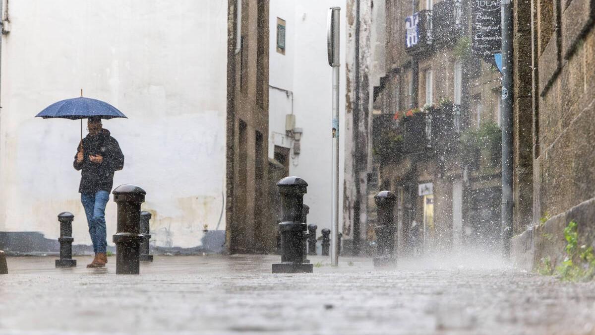 Un hombre camina por la zona vieja de Santiago un día de intensas lluvias