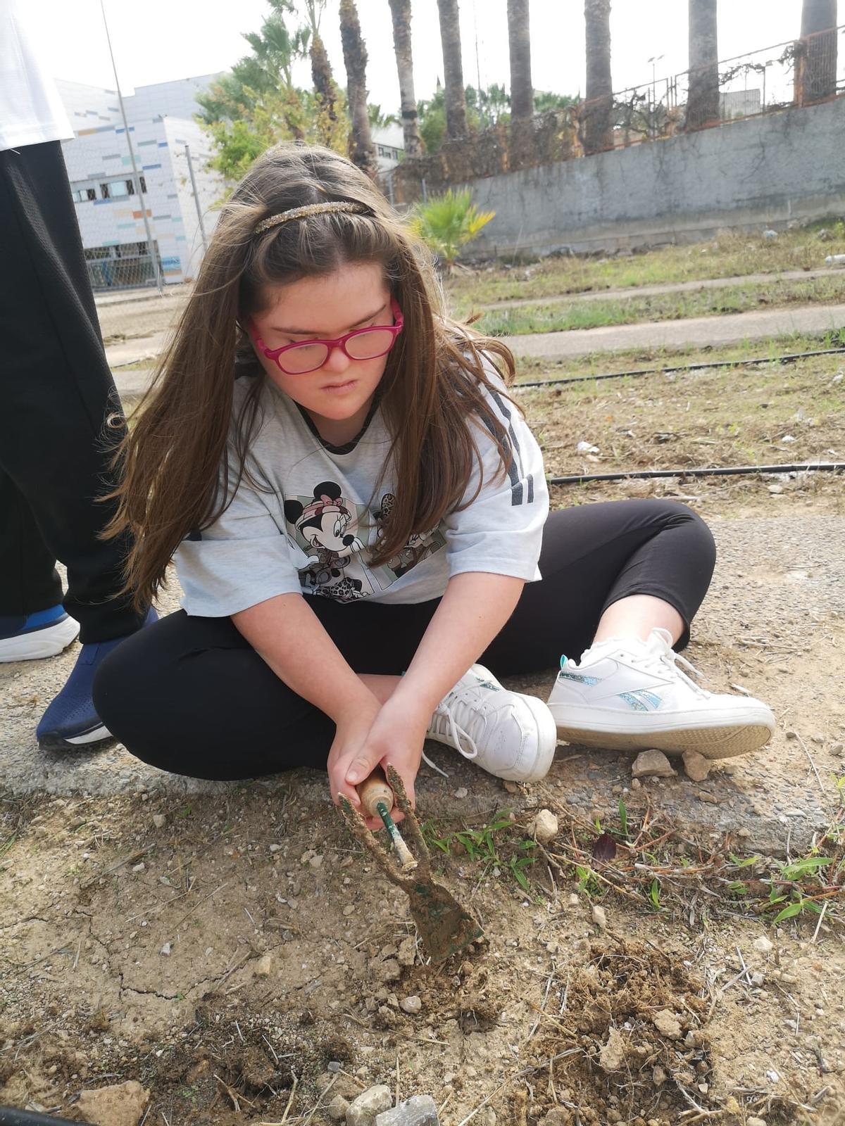 Una alumna birbant les males herbes de l'Hort de l'IES Torís.