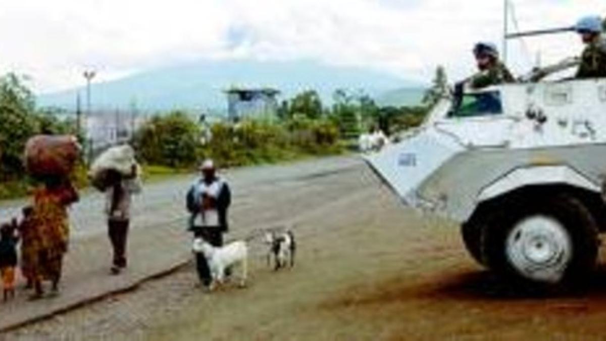 Unos refugiados congoleños pasan por delante de un tanque de la ONU junto a la sede de los cascos azules en Goma.