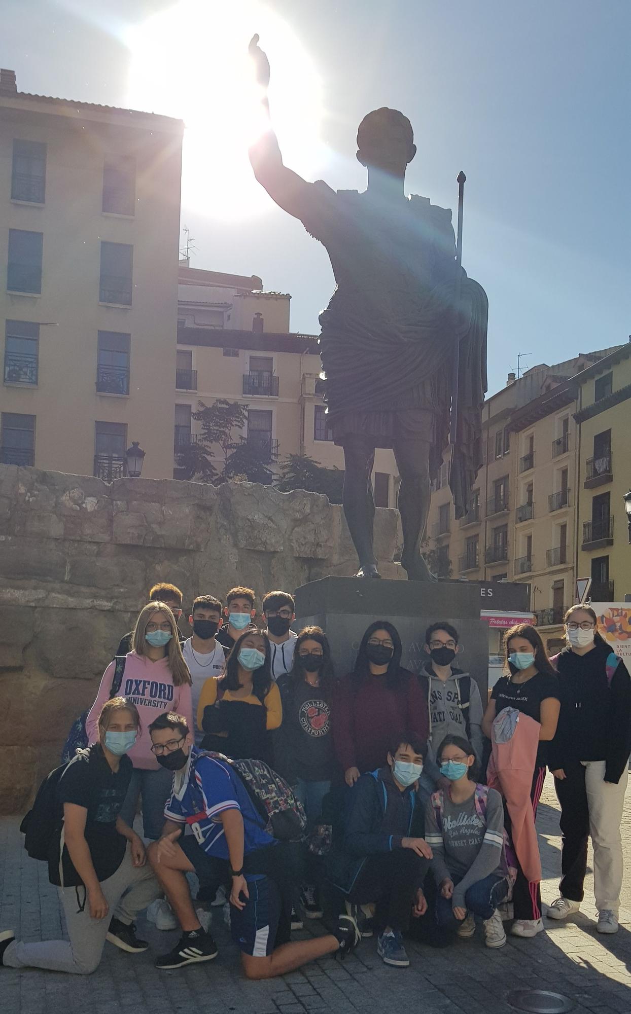 Alumnos y alumnas, junto a la estatua del emperador César Augusto, junto a las murallas romanas.