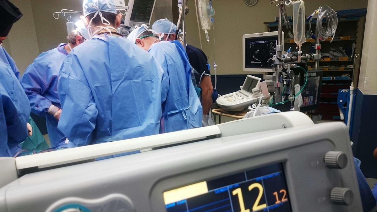 Una consola de soporte vital (primer plano) y un grupo de médicos durante una operación.