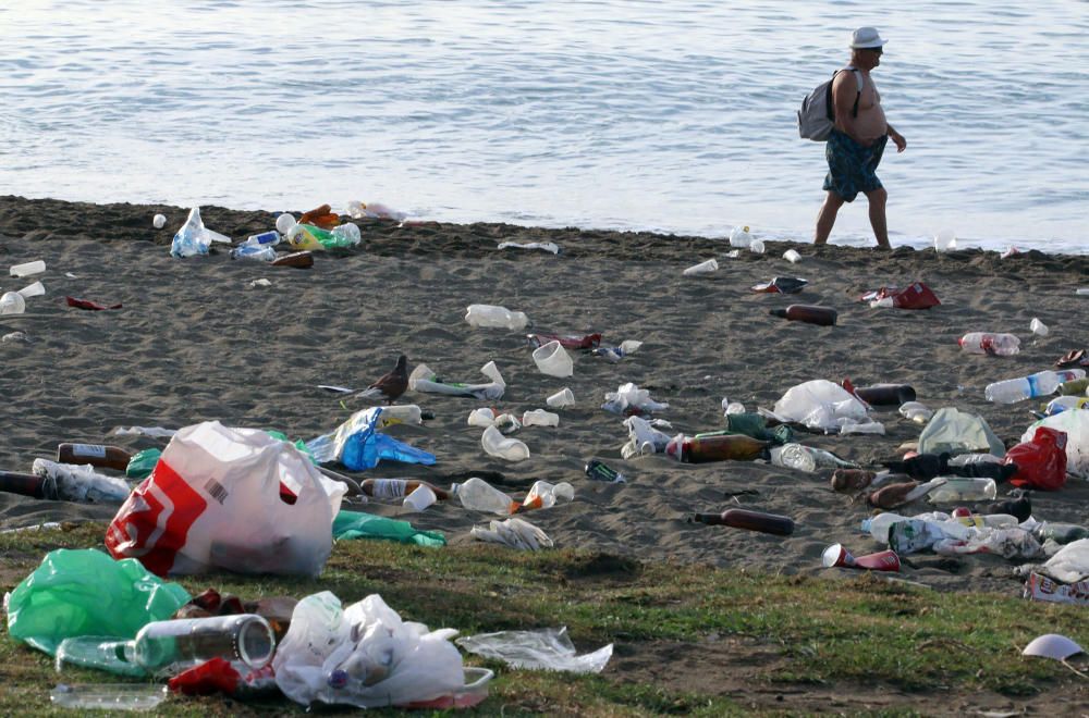 Los operarios de los servicios de limpieza trabajan para dejar la playa en óptimas condiciones tras una larga noche de fiesta en la arena