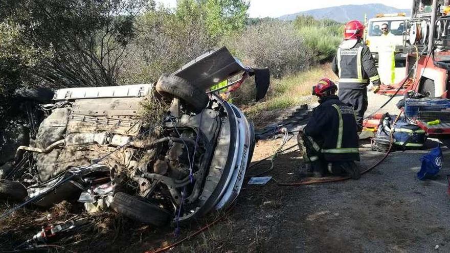 Los bomberos junto al vehículo siniestrado de donde rescataron a los dos ocupantes.