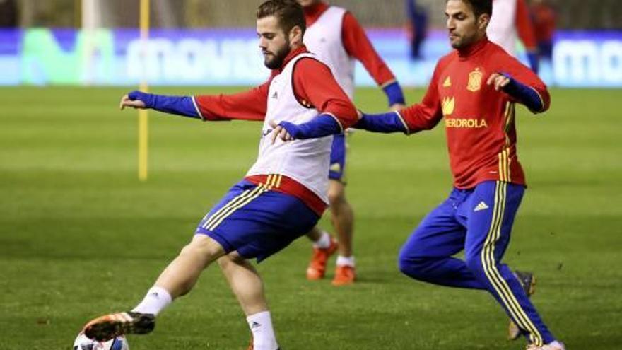 Nacho Fernández, con el balón seguido por su compañero, Cesc, durante el entrenamiento de ayer en Bruselas.