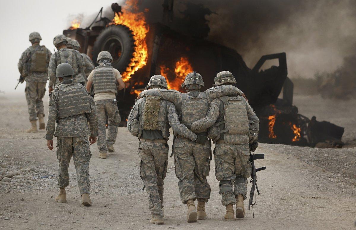 A soldier with an injured ankle from the US Army’s 1-320 Field Artillery Regiment, 101st Airborne Division is assisted past his burning M-ATV armored vehicle after it struck an Improvised Explosive Device (IED) on a road near Combat Outpost Nolen in the Arghandab Valley in this picture taken July 23, 2010. None of the four soldiers in the vehicle were seriously injured in the explosion. Picture taken July 23, 2010. REUTERS/Bob Strong  (AFGHANISTAN - Tags: CONFLICT MILITARY)