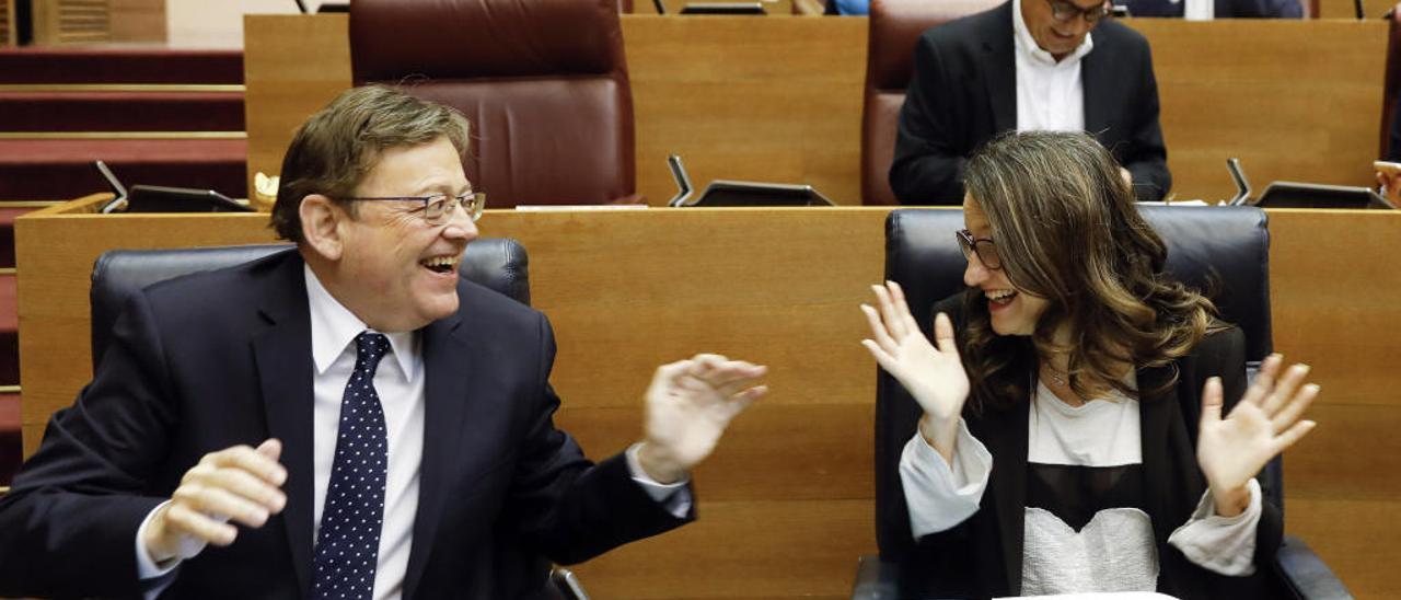 El president de la Generalitat, Ximo Puig, y la vicepresidenta, Mónica Oltra, bromean durante la sesión de control del pleno de Les Corts
