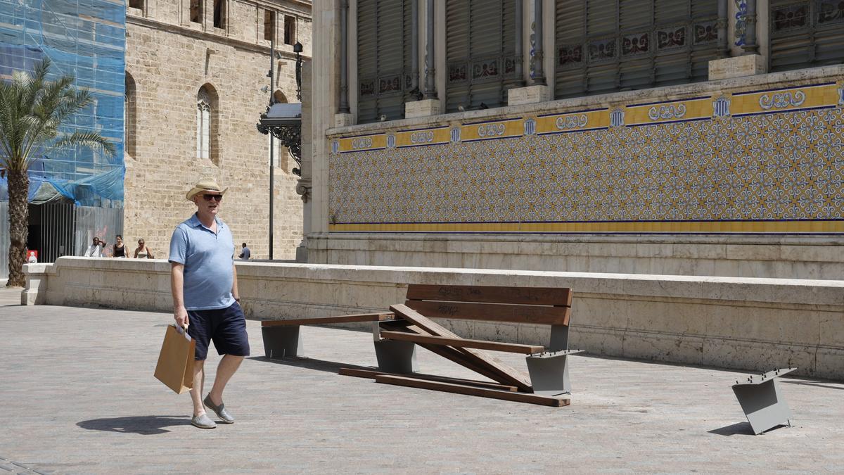 Un hombre pasea junto al banco destrozado junto al Mercado Central.