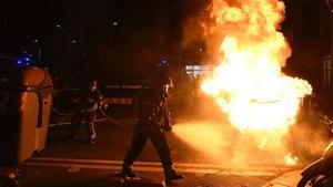 Bomberos apagan un contenedor en llamas en las protestas de los manifestantes contra un acto de Vox.