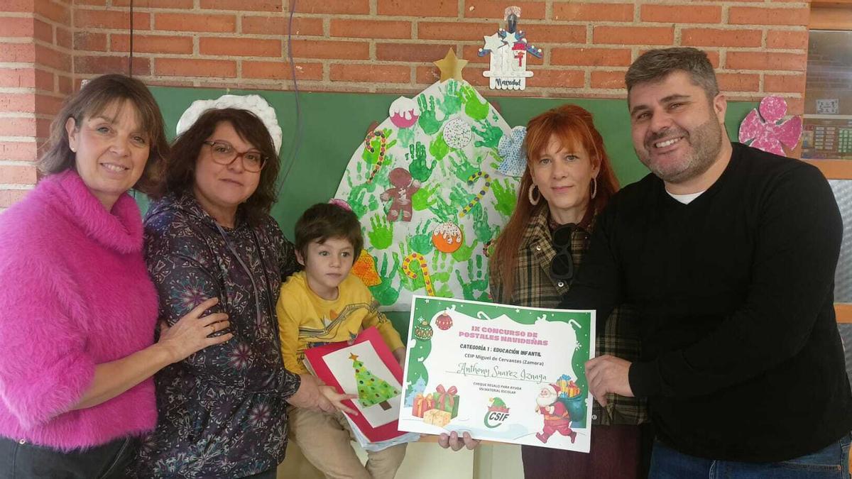 Anthony Suárez Iznaga sujeta la postal ganadora junto a sus padres y profesoras.