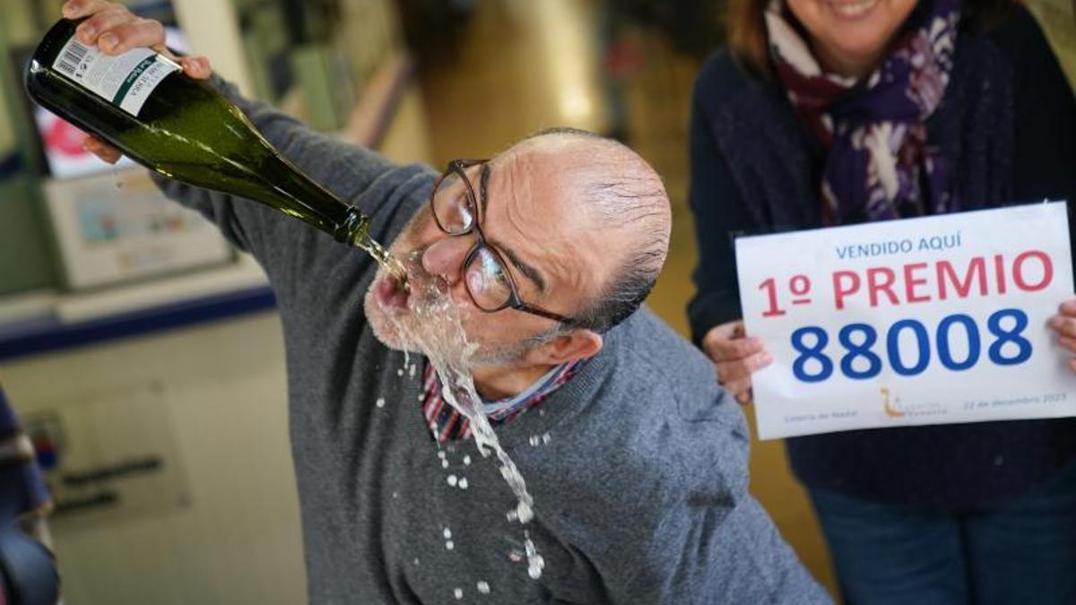 Un empleado de la administración loterías 'Venecia' celebra que han vendido parte del número 88008 correspondiente al primer premio del Sorteo Extraordinario de la Lotería de Navidad en Santiago de Compostela