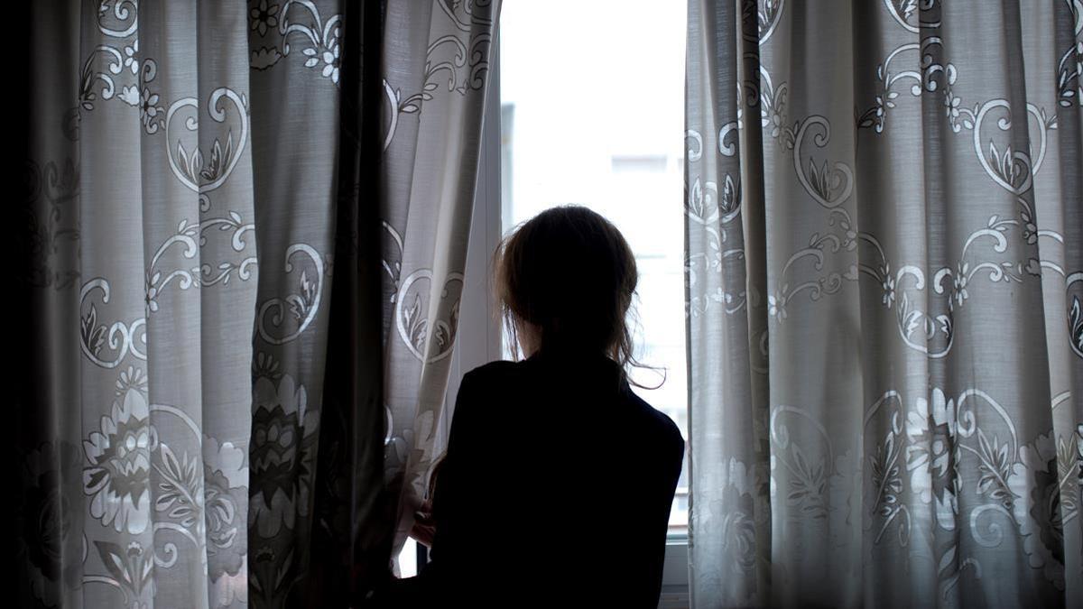 Una mujer observa a través de la ventana de su vivienda en Ourense durante el confinamiento, el pasado 19 de abril