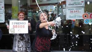 Las loteras María Jesus (d) y Begoña celebran el reparto del quinto premio de la lotería de Navidad, que le ha tocado al número 58808, en un punto de venta de la calle Castaños de la capital vizcaína.